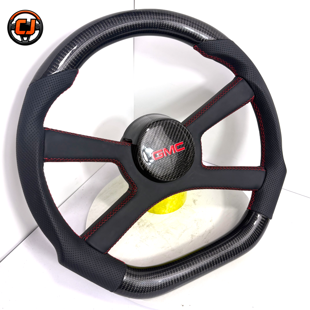 Custom GMC carbon fiber steering wheel with glossy carbon fiber rim, black perforated leather grips, red contrast stitching and carbon fiber GMC center cover