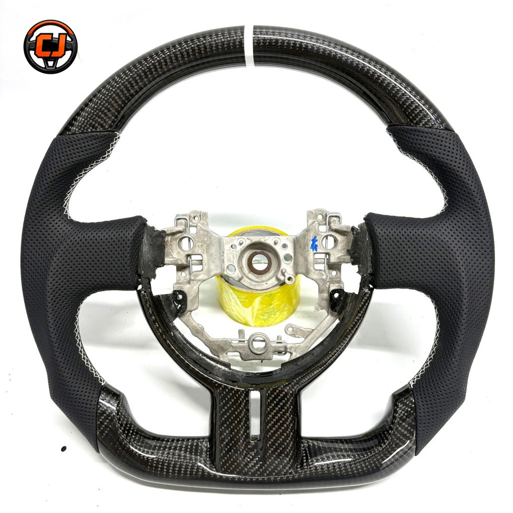 Toyota GT86 performance steering wheel crafted from premium carbon fiber with white stitching, sculpted grips and flat-bottom racing design by CJ Mod Garage