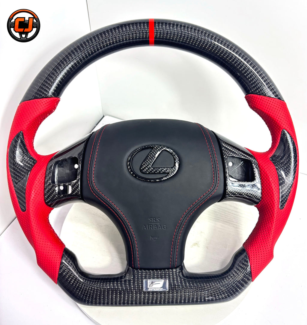 Close up product image of custom Lexus IS carbon fiber steering wheel with red perforated leather sides, black airbag cover, red stitching and carbon fiber Lexus emblem