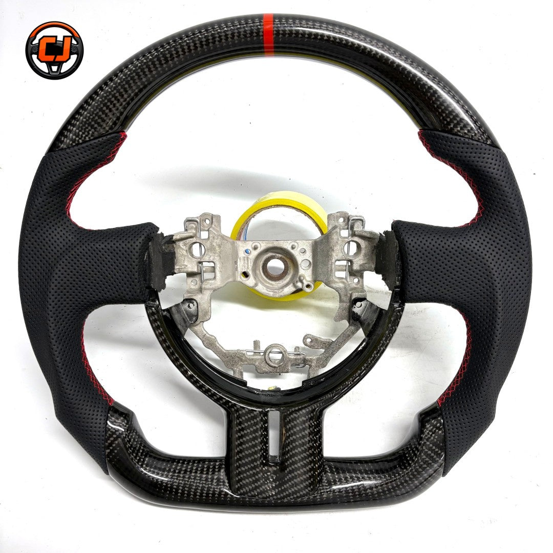 Custom Toyota GT86 steering wheel built with premium carbon fiber and perforated leather, accented by red stitching and racing-inspired center marker by CJ Mod Garage