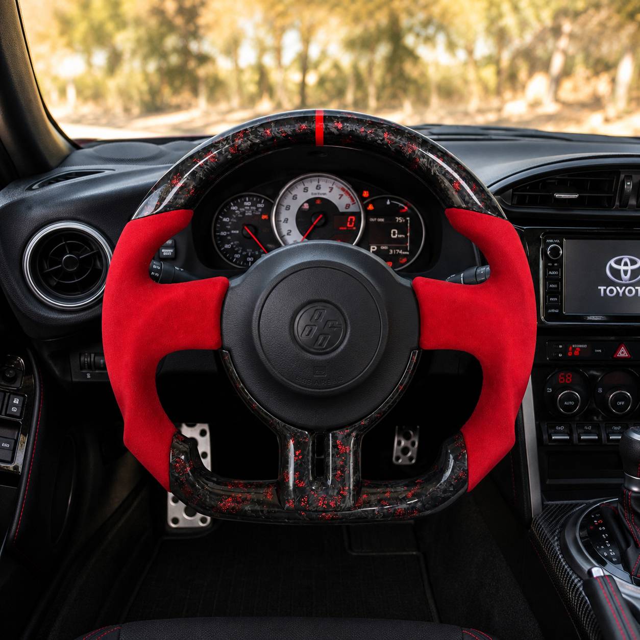 Toyota GT86 forged carbon steering wheel with metallic red flakes, red Alcantara side grips and flat-bottom racing profile installed in vehicle interior by CJ Mod Garage