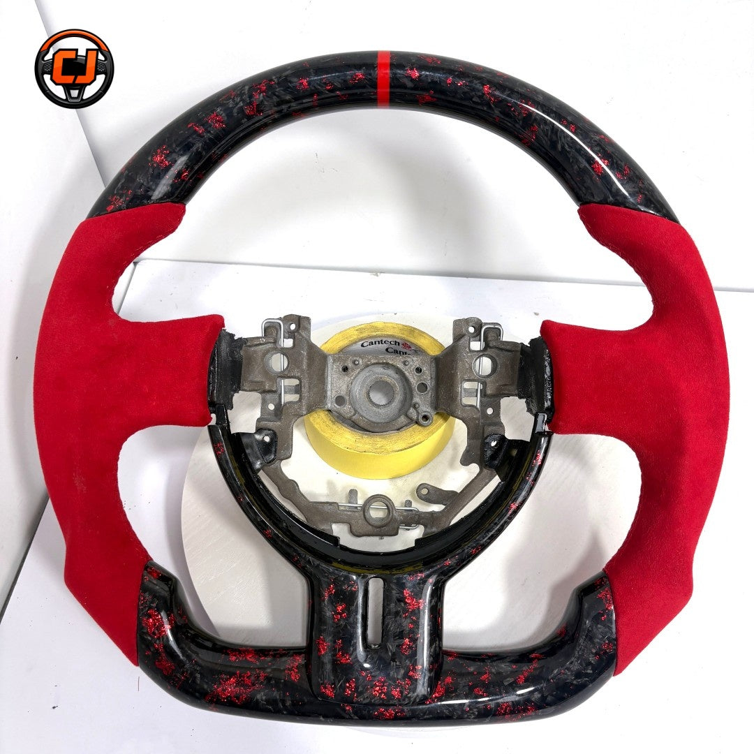 Toyota GT86 performance steering wheel crafted from forged carbon fiber with red metallic flakes, Alcantara grips and sport flat-bottom geometry by CJ Mod Garage