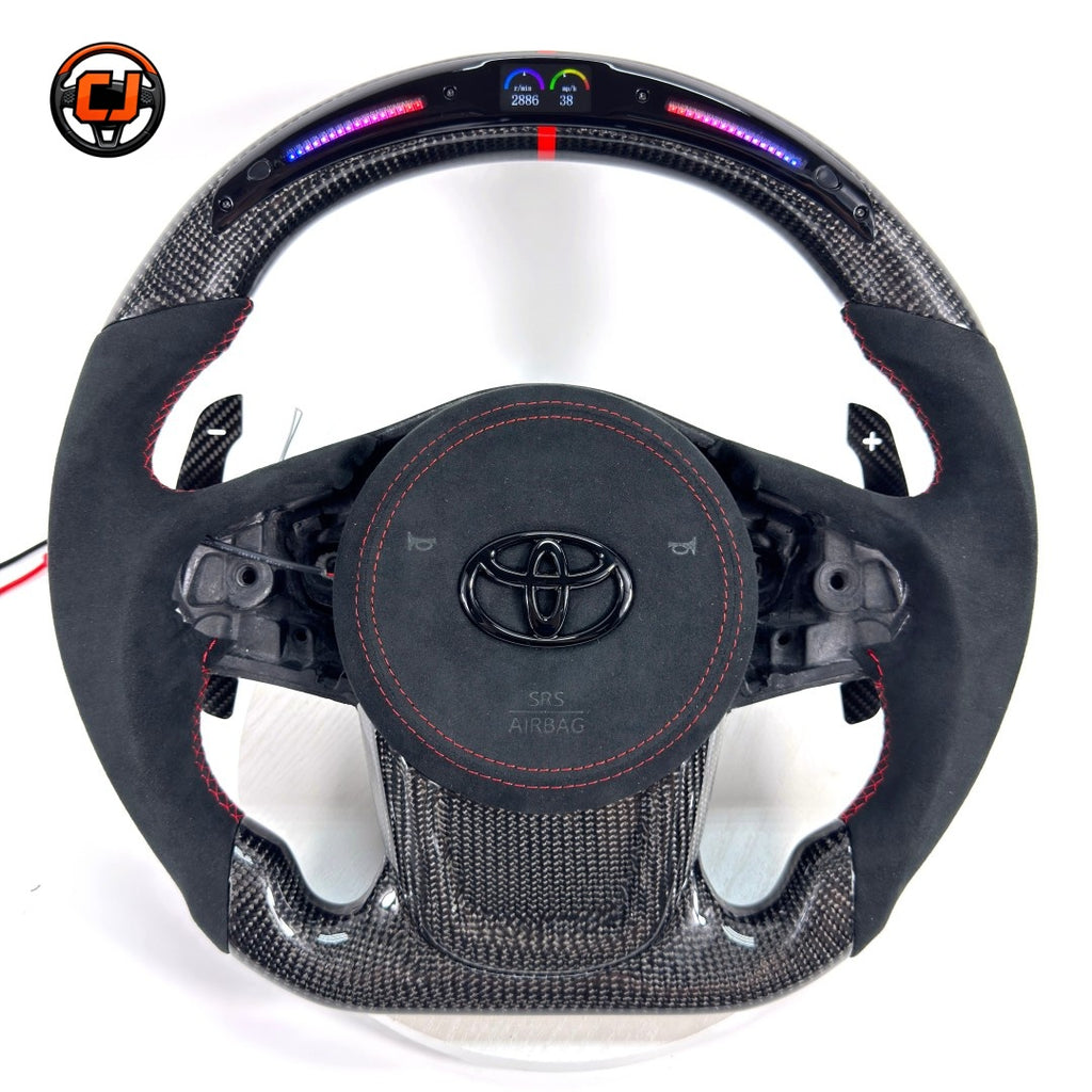 Custom Toyota GR Supra A90 A91 steering wheel crafted with premium carbon fiber, Alcantara wrapping, integrated LED shift lights, red center stripe and paddle shifters by CJ Mod Garage