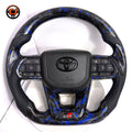 Toyota Land Cruiser GR Sport steering wheel crafted with blue flake forged carbon style trim premium perforated leather and factory style airbag cover by CJ Mod Garage