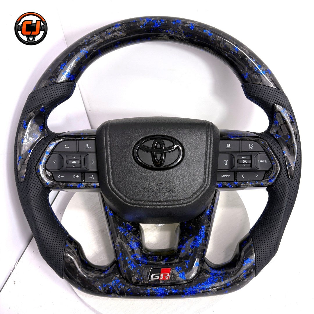 Toyota Land Cruiser GR Sport steering wheel crafted with blue flake forged carbon style trim premium perforated leather and factory style airbag cover by CJ Mod Garage