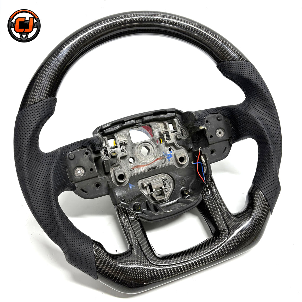 Custom carbon fiber steering wheel for Range Rover Evoque with black perforated leather side grips, glossy carbon fiber upper and lower sections, flat bottom design and exposed button mounting area
