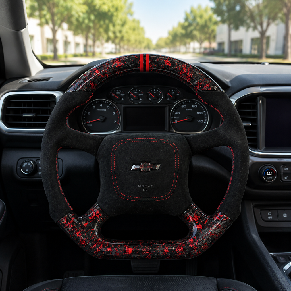 Front interior view of custom Chevrolet steering wheel with black Alcantara grip, red contrast stitching, red forged carbon fiber upper and lower trim and Chevrolet logo airbag cover
