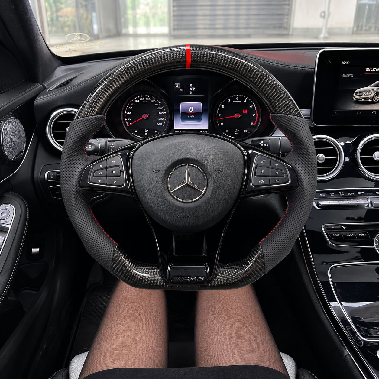 Front driver view of a Mercedes-Benz W205 AMG custom steering wheel with gloss carbon fiber, perforated leather and red stitching by CJ Mod Garage.