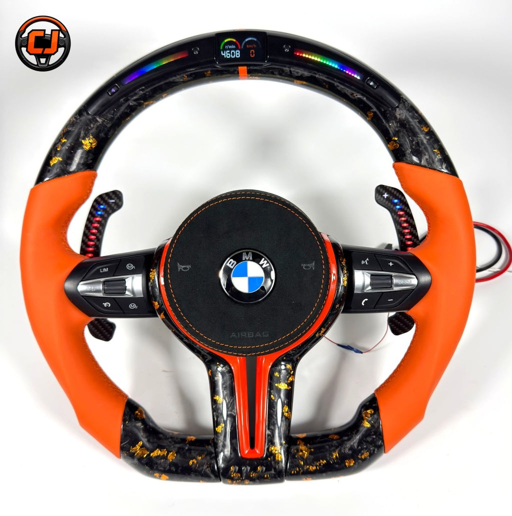 Orange leather BMW forged carbon fiber steering wheel with gold flake carbon finish, LED shift lights, digital RPM display, multifunction controls, and carbon paddle shifters compatible with BMW F10 F11 F15 F18 F20 F23 F25 F30 F32 F35 F40 F80 E84 E87 E90 E92 E93