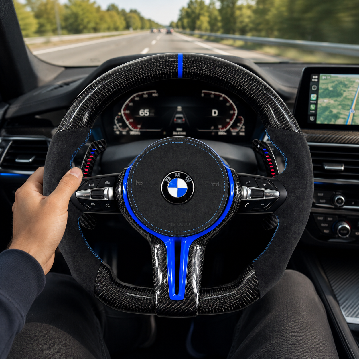 Custom BMW carbon fiber steering wheel with blue center stripe, Alcantara grips, LED paddle shifters, and gloss carbon finish installed in BMW F10 F11 F15 F18 F20 F23 F25 F30 F32 F35 F40 F80 E84 E87 E90 E92 E93 driving interior