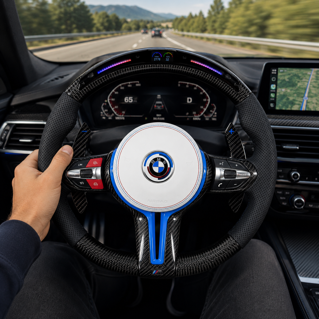 Custom BMW carbon fiber steering wheel with white airbag cover, blue accent trim, LED shift light display, perforated leather grips, and carbon paddle shifters installed in BMW F10 F11 F15 F18 F20 F23 F25 F30 F32 F35 F40 F80 E84 E87 E90 E92 E93 driving interior