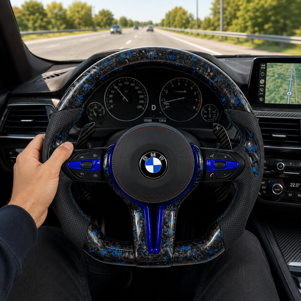 BMW custom forged carbon steering wheel with blue marble flakes, blue accent trim, perforated leather grips, carbon paddle shifters, and round airbag cover installed in BMW F10 F11 F15 F18 F20 F23 F25 F30 F32 F35 F40 F80 E84 E87 E90 E92 E93 interior driving scene
