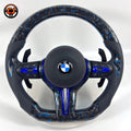BMW forged carbon steering wheel with blue marble carbon finish, blue center accent, black perforated leather grips, carbon paddle shifters, and round airbag cover for BMW F10 F11 F15 F18 F20 F23 F25 F30 F32 F35 F40 F80 E84 E87 E90 E92 E93