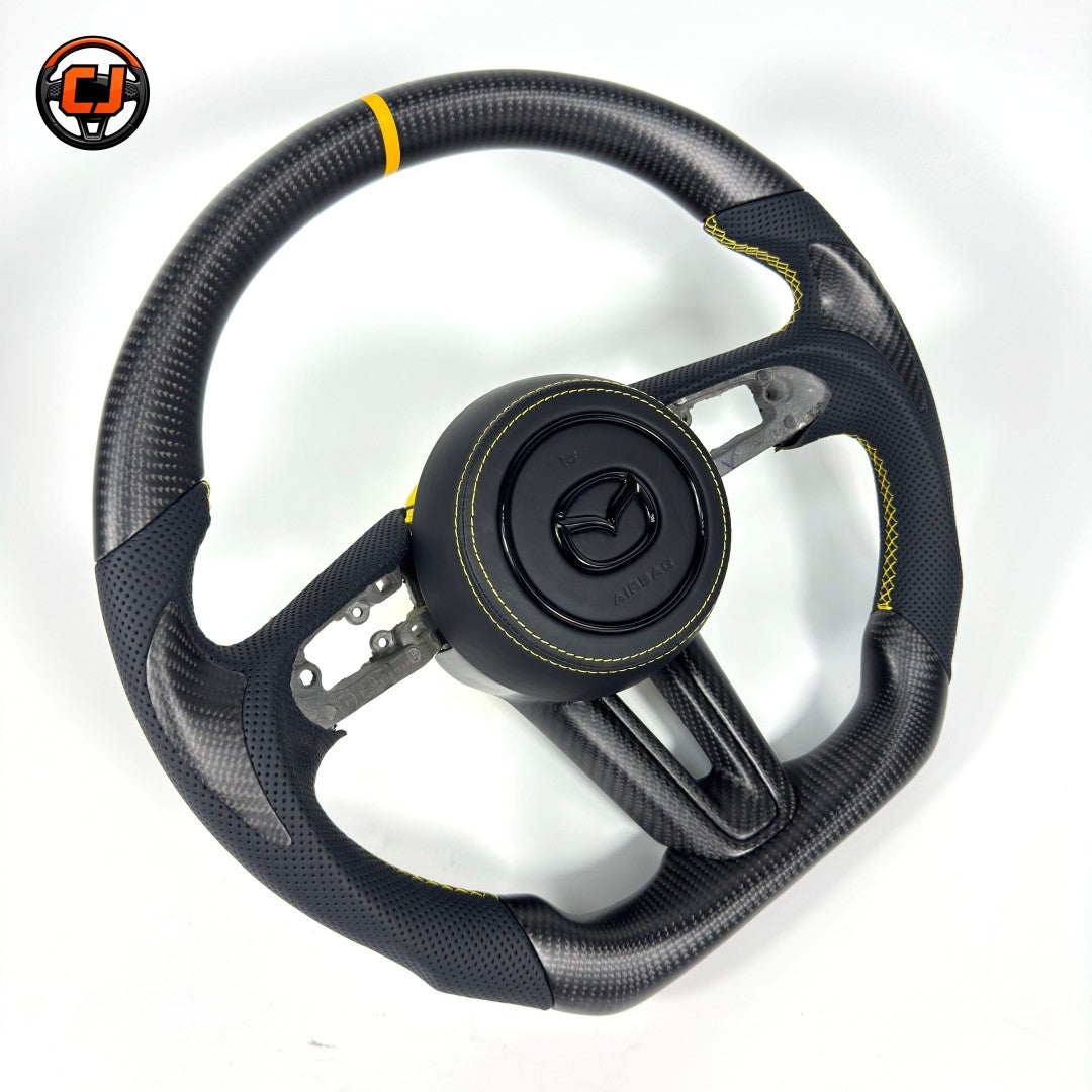 Custom Mazda 3 Axela carbon fiber steering wheel with yellow center stripe black perforated leather grips yellow stitching and flat bottom design