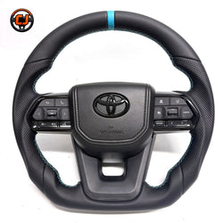 Toyota Land Cruiser LC300 handcrafted leather steering wheel with perforated grip sections, blue contrast stitching, OEM airbag cover and factory-style controls by CJ Mod Garage
