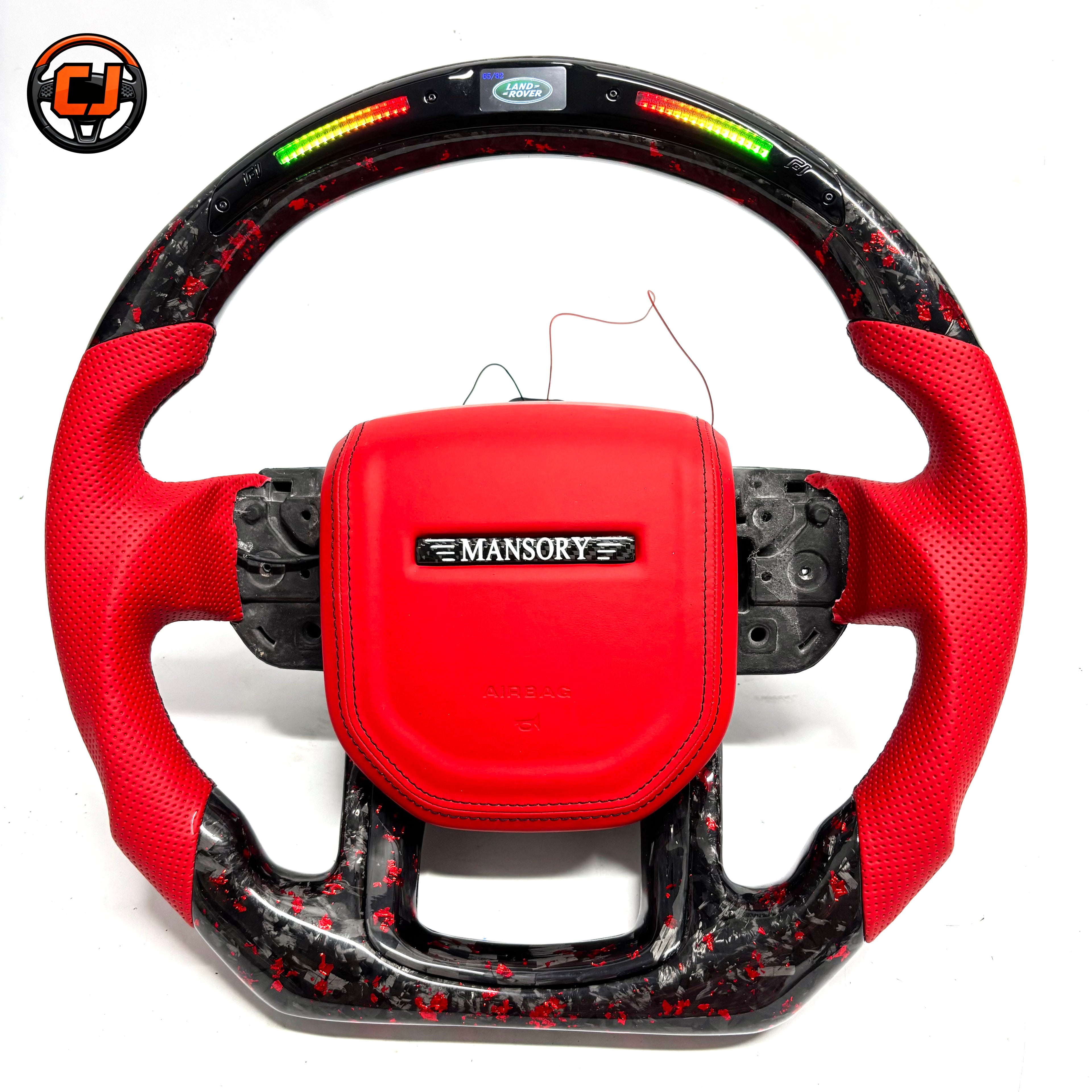 Studio product photo of custom Land Rover Range Rover steering wheel with red leather airbag cover, red perforated leather grips, LED shift lights and red black forged carbon fiber trim