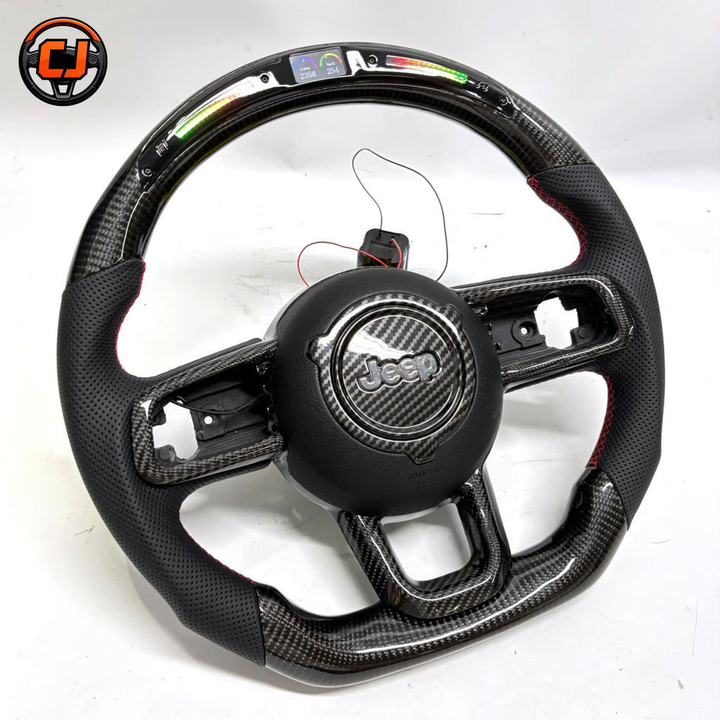 Angled studio view of custom Jeep Wrangler carbon fiber steering wheel with black perforated leather grips, glossy carbon fiber trim, flat bottom shape and black Jeep airbag cover