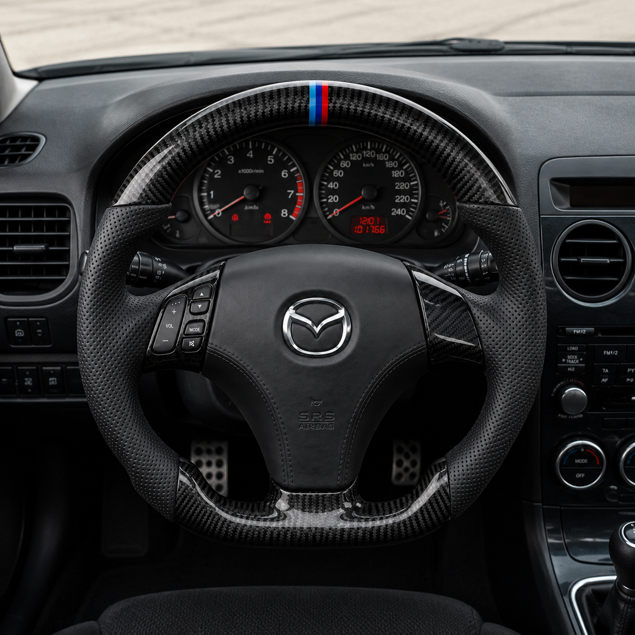 Custom Mazda steering wheel in vehicle interior with carbon fiber finish blue red center stripe and sport flat bottom design