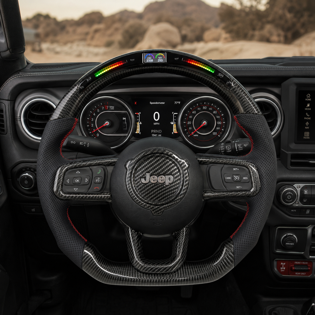 Front interior view of custom Jeep Wrangler steering wheel with glossy carbon fiber rim, black perforated leather grips, red stitching, LED shift light display and Jeep airbag cover