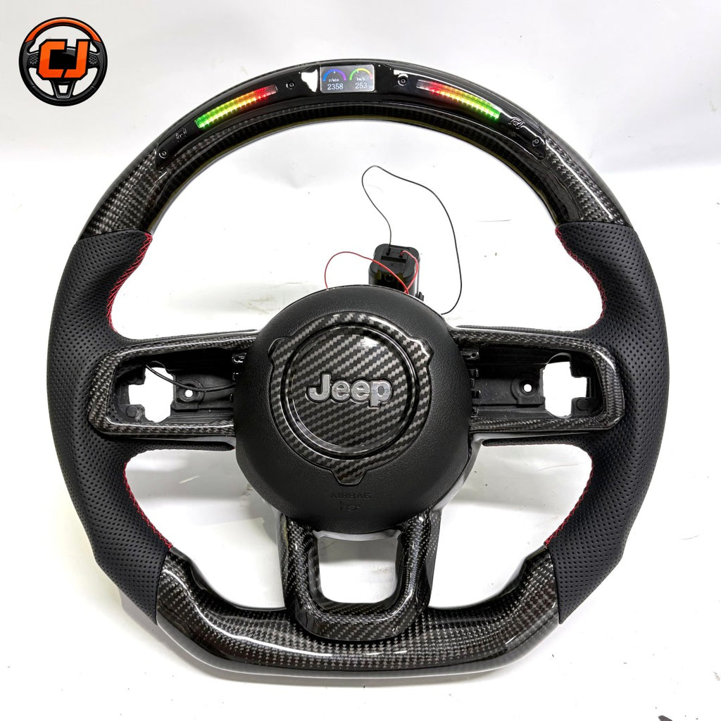 Studio product photo of custom Jeep Wrangler carbon fiber steering wheel with LED shift lights, top digital display, black perforated leather grips, flat bottom design and exposed button openings