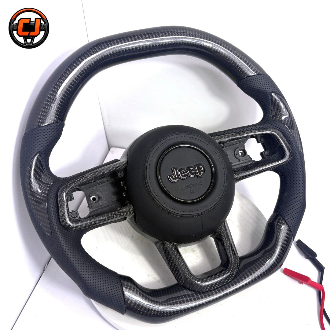 Custom Jeep Wrangler LED carbon fiber steering wheel installed in off-road interior with black perforated leather grips, red stitching, top digital display, LED shift lights and black Jeep airbag cover