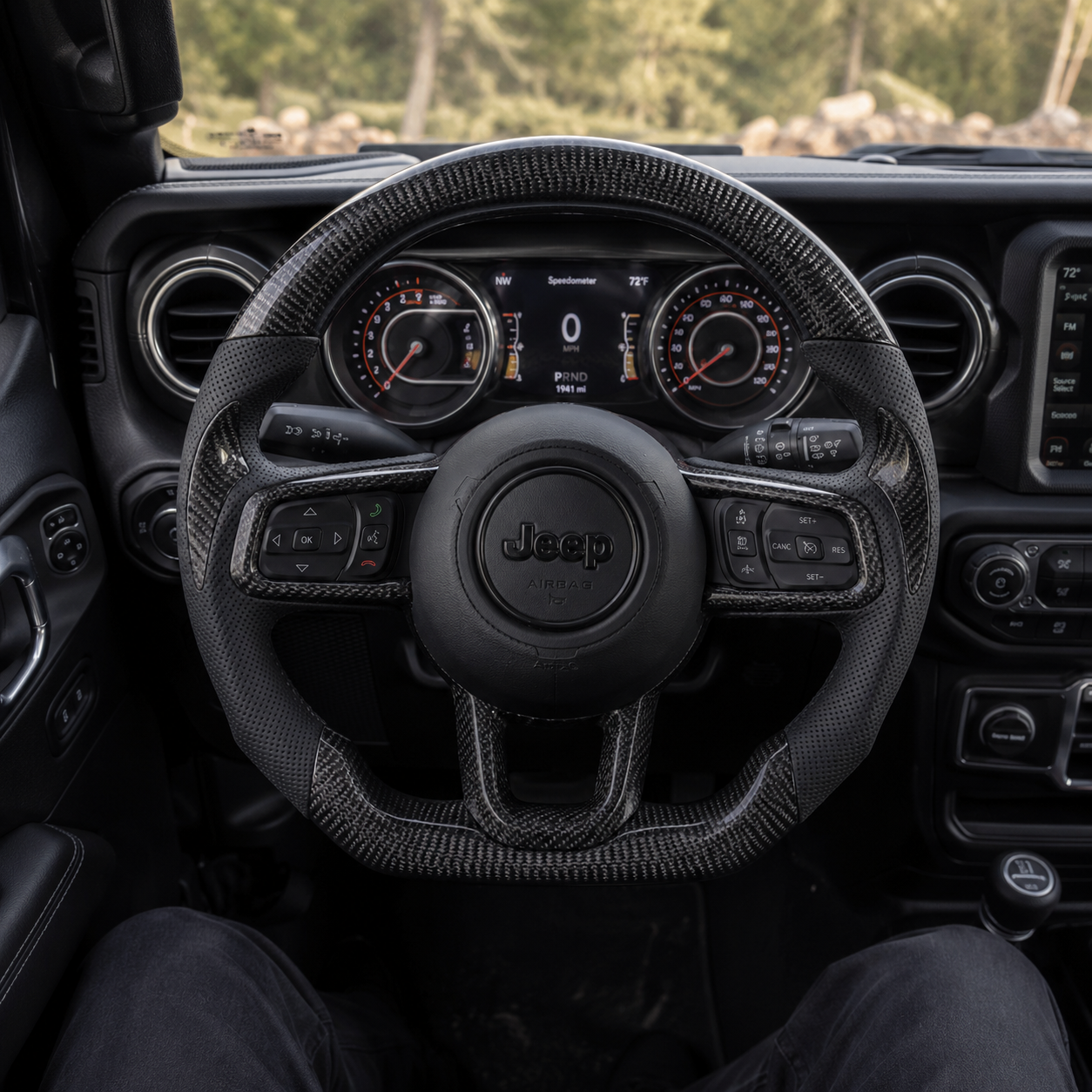 Angled studio view of custom Jeep Wrangler carbon fiber steering wheel with black perforated leather grips, glossy carbon fiber trim, black Jeep airbag cover and flat bottom sport design