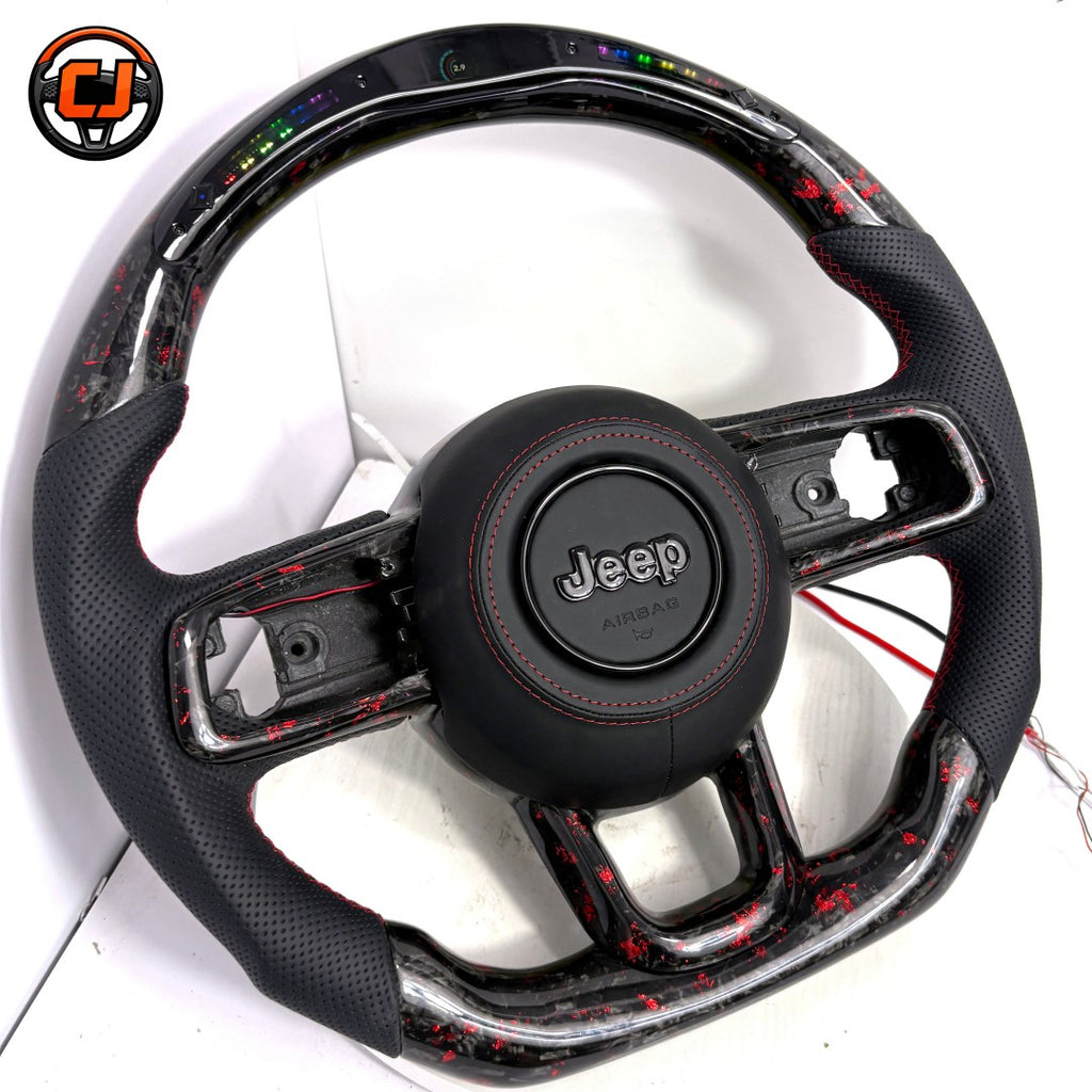 Angled studio product photo of custom Jeep Wrangler LED steering wheel with black perforated leather grips, red stitching, red flake forged carbon fiber trim, top LED shift light display and flat bottom design