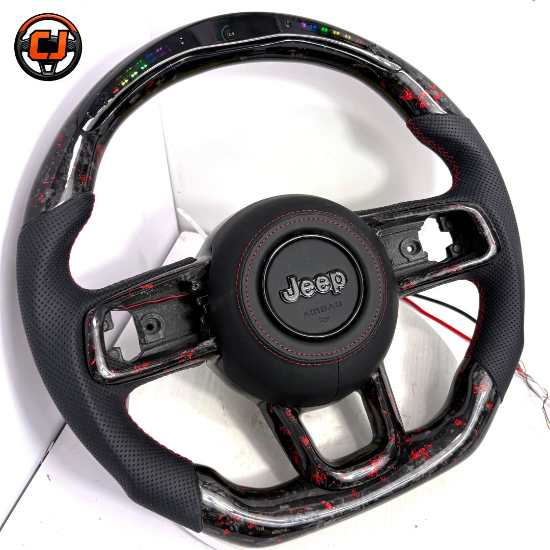 Angled studio product photo of custom Jeep Wrangler LED steering wheel with black perforated leather grips, red stitching, red flake forged carbon fiber trim, top LED shift light display and flat bottom design
