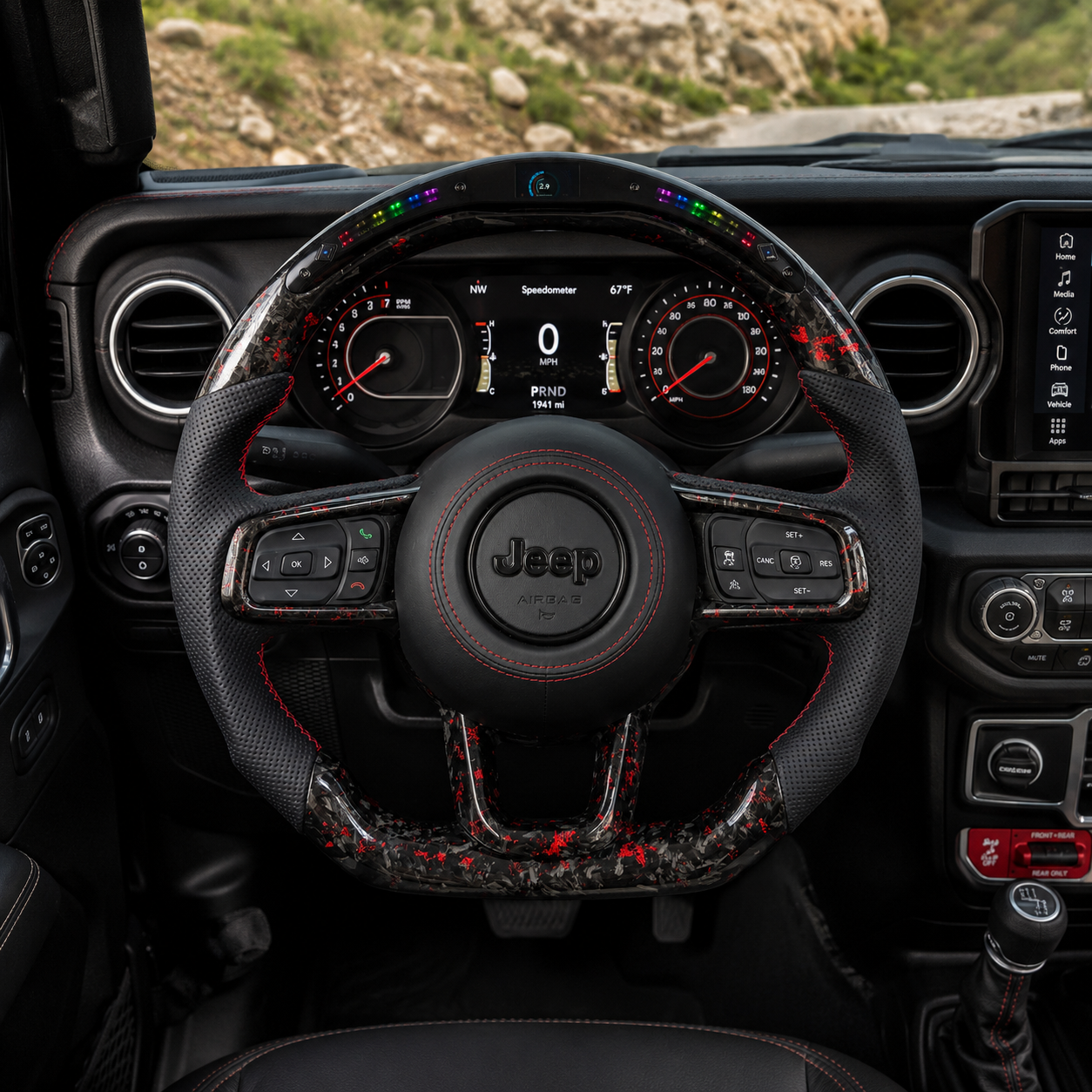 Front interior view of custom Jeep Wrangler steering wheel with LED shift lights, black perforated leather side grips, black Jeep airbag cover, red stitching and red black forged carbon fiber flat bottom trim