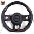 Studio front view of custom Jeep Wrangler LED carbon fiber steering wheel with black perforated leather grips, red stitching, black Jeep airbag cover, exposed button openings and red flake carbon fiber trim