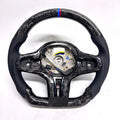 CJ Mod Garage BMW G-chassis forged carbon fiber steering wheel on white background featuring gloss forged carbon construction, perforated black leather side grips, flat-bottom performance shape, M tricolor 12 o’clock stripe, exposed mounting structure for OEM buttons and airbag components, compatible with BMW G02 G05 G06 G09 G11 G12 G15 G20 G22 G28 G29 G30 G38 G80 G82 F40 F90