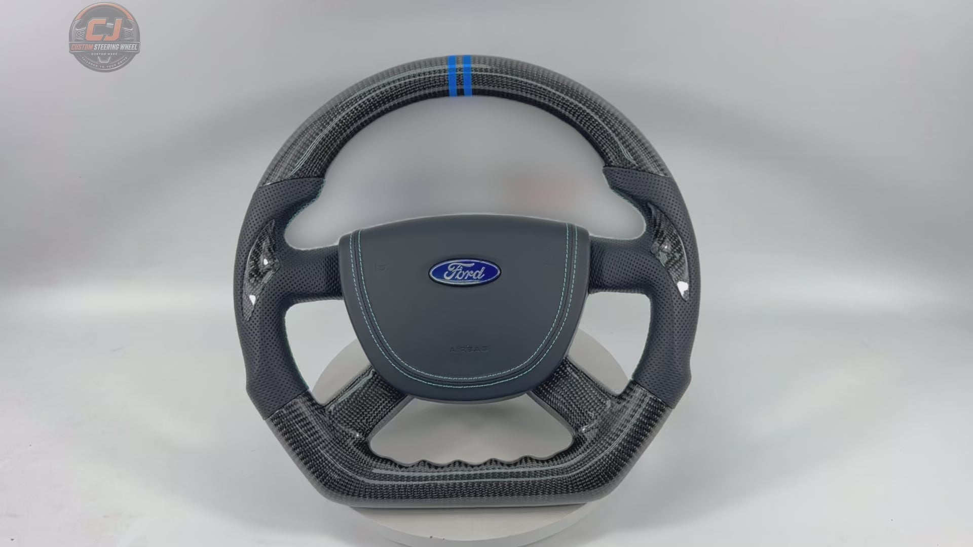 Rotating product video of Ford Focus RS ST carbon fiber steering wheel with perforated leather grips, blue stitching, blue 12 o’clock marker, airbag cover and sport contour design by CJ Mod Garage