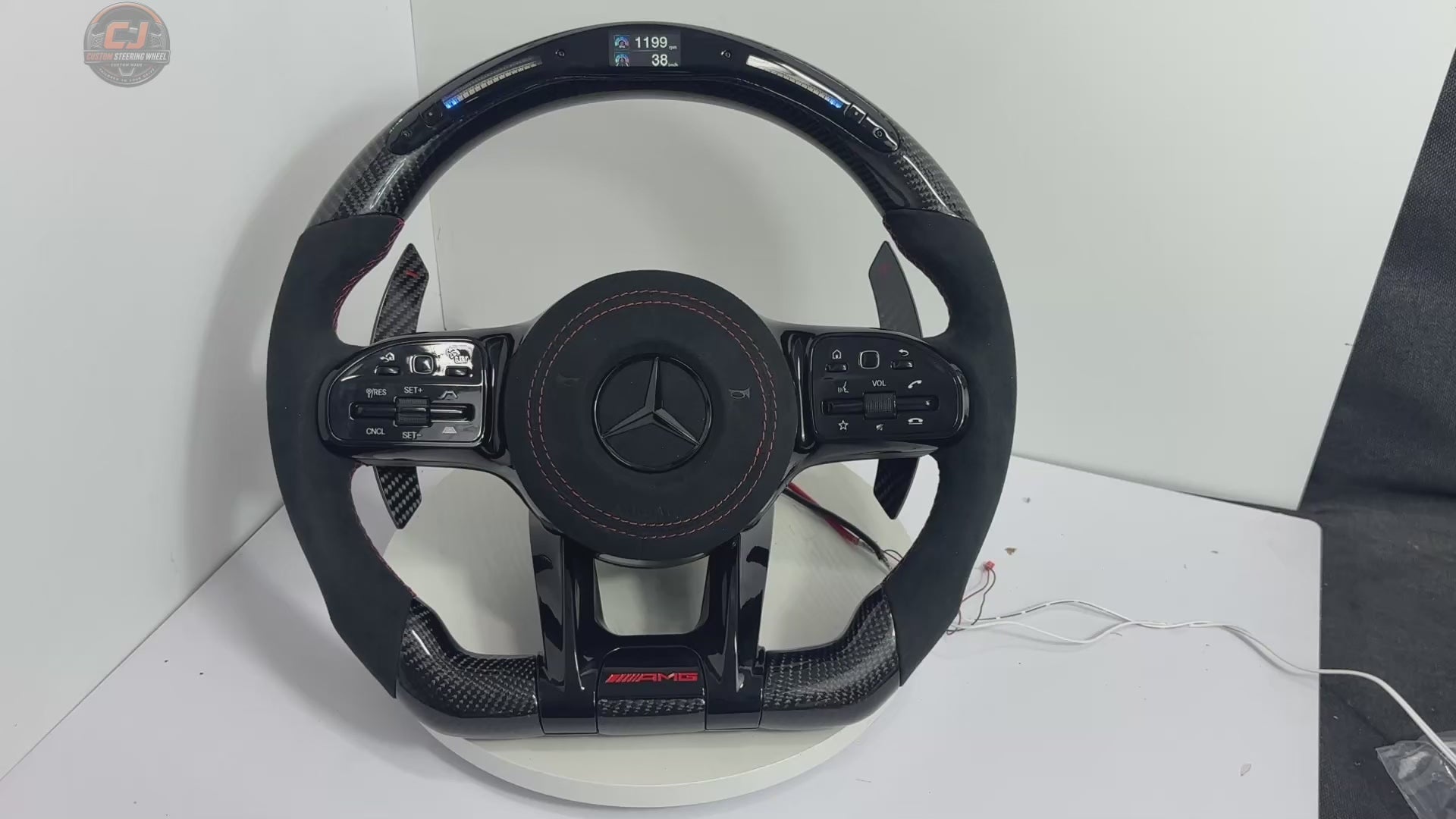 White background video of Mercedes AMG custom steering wheel with forged carbon finish, LED shift lights, Alcantara grip and paddle shifters for W117 W176 W177 W203 W204 W205 W211 W212 W213 W218 C43 C63 C200 C300 by CJ Mod Garage