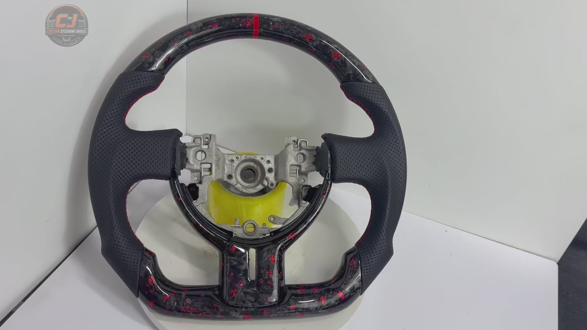 360-degree studio video of Toyota GT86 forged carbon fiber steering wheel with red flake finish, perforated leather grips, red stitching and flat-bottom motorsport styling by CJ Mod Garage