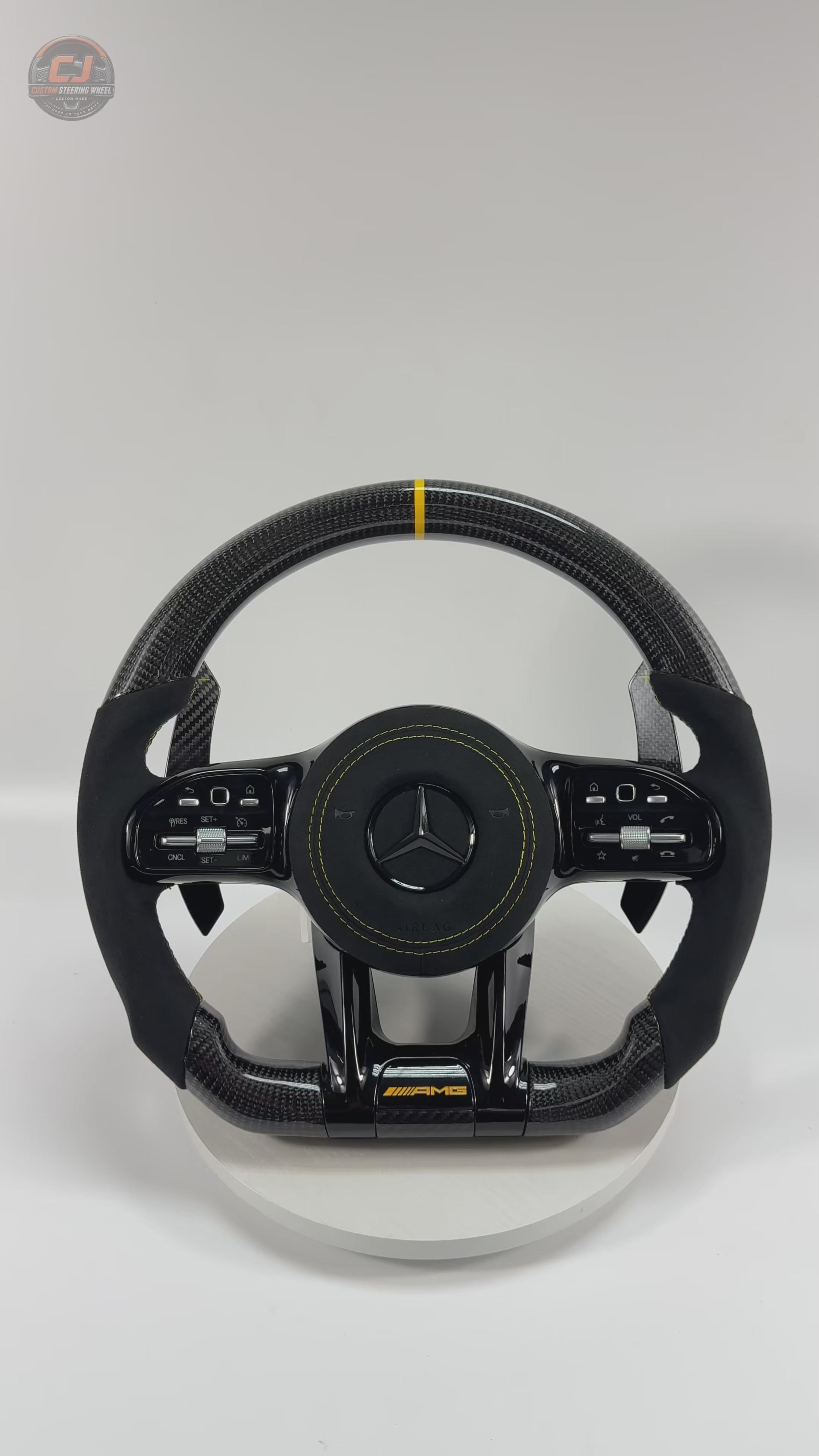 White background video showing Mercedes AMG carbon fiber steering wheel with yellow twelve clock stripe Alcantara grips carbon paddle shifters and sporty airbag cover for W117 W176 W177 W203 W204 W205 W211 W212 W213 W218 C43 C63 C200 C300 CJ Mod Garage