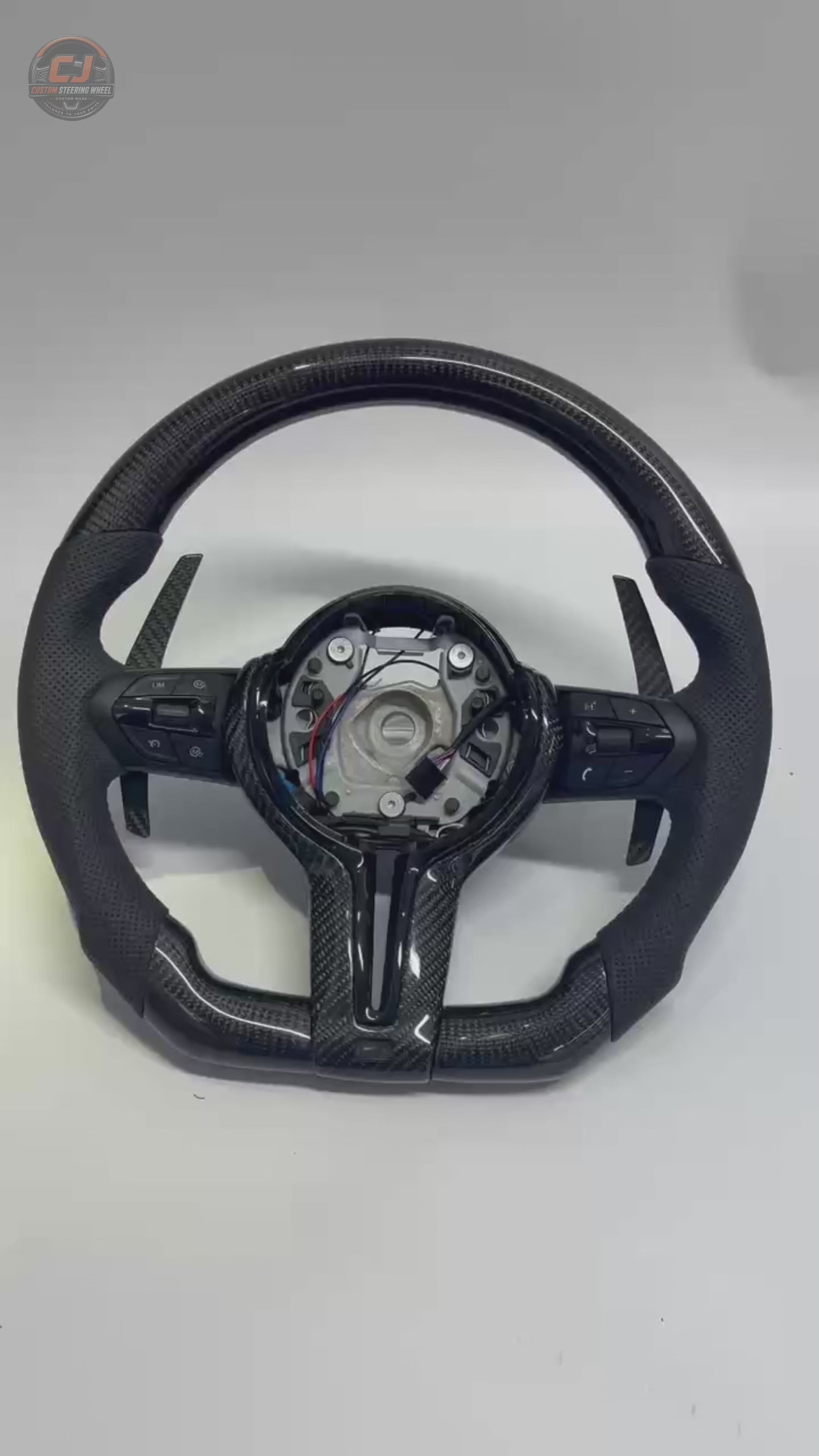 Custom BMW carbon fiber steering wheel featuring gloss carbon fiber, perforated leather grips, paddle shifters, and flat-bottom sport design. Compatible with BMW 1 Series, 2 Series, 3 Series, and 4 Series models.