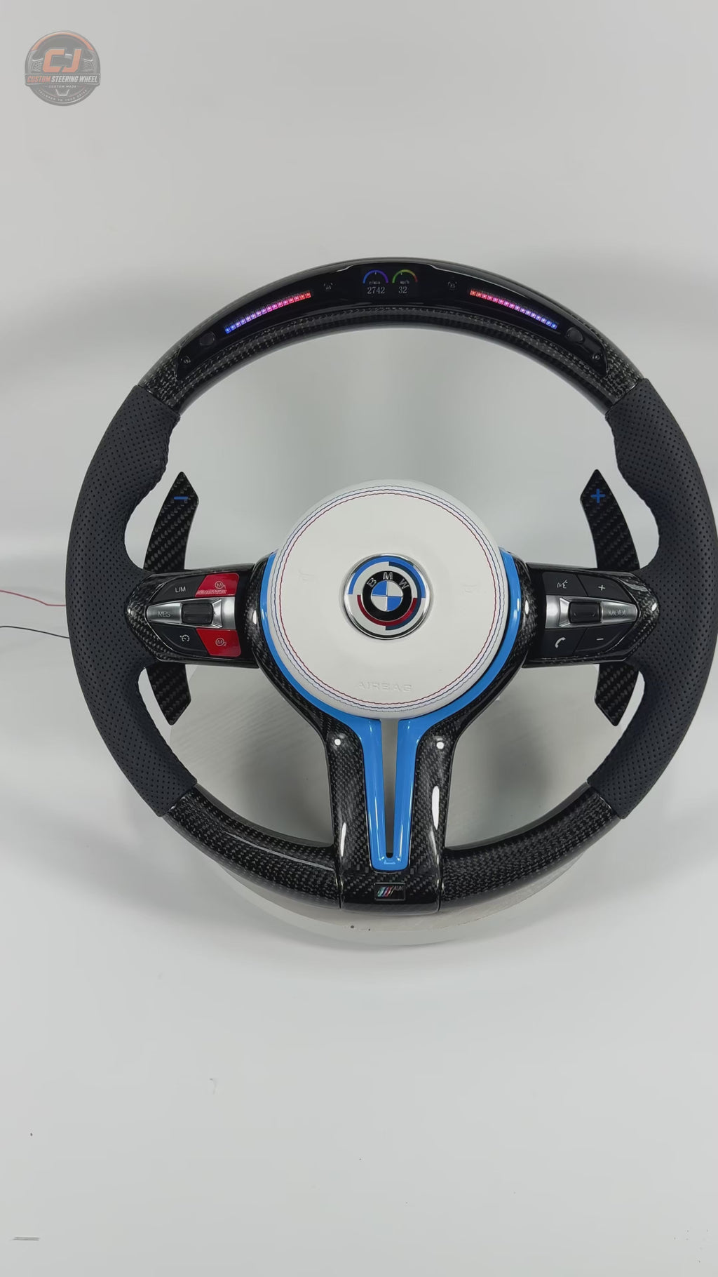White background product showcase video of BMW custom carbon fiber steering wheel with white airbag cover, blue accent trim, LED shift lights, multifunction buttons, and carbon paddle shifters for BMW F10 F11 F15 F18 F20 F23 F25 F30 F32 F35 F40 F80 E84 E87 E90 E92 E93
