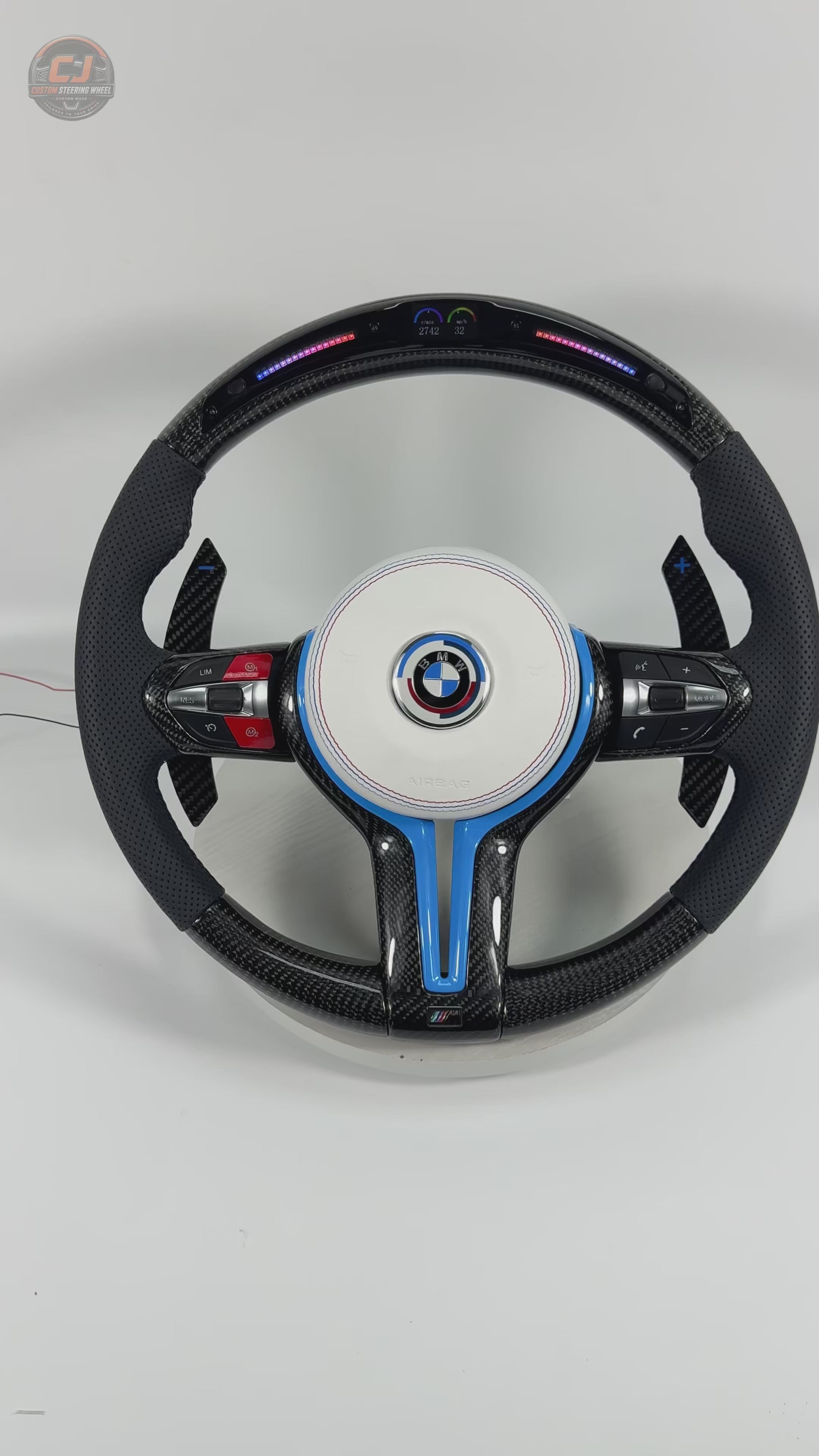 White background product showcase video of BMW custom carbon fiber steering wheel with white airbag cover, blue accent trim, LED shift lights, multifunction buttons, and carbon paddle shifters for BMW F10 F11 F15 F18 F20 F23 F25 F30 F32 F35 F40 F80 E84 E87 E90 E92 E93