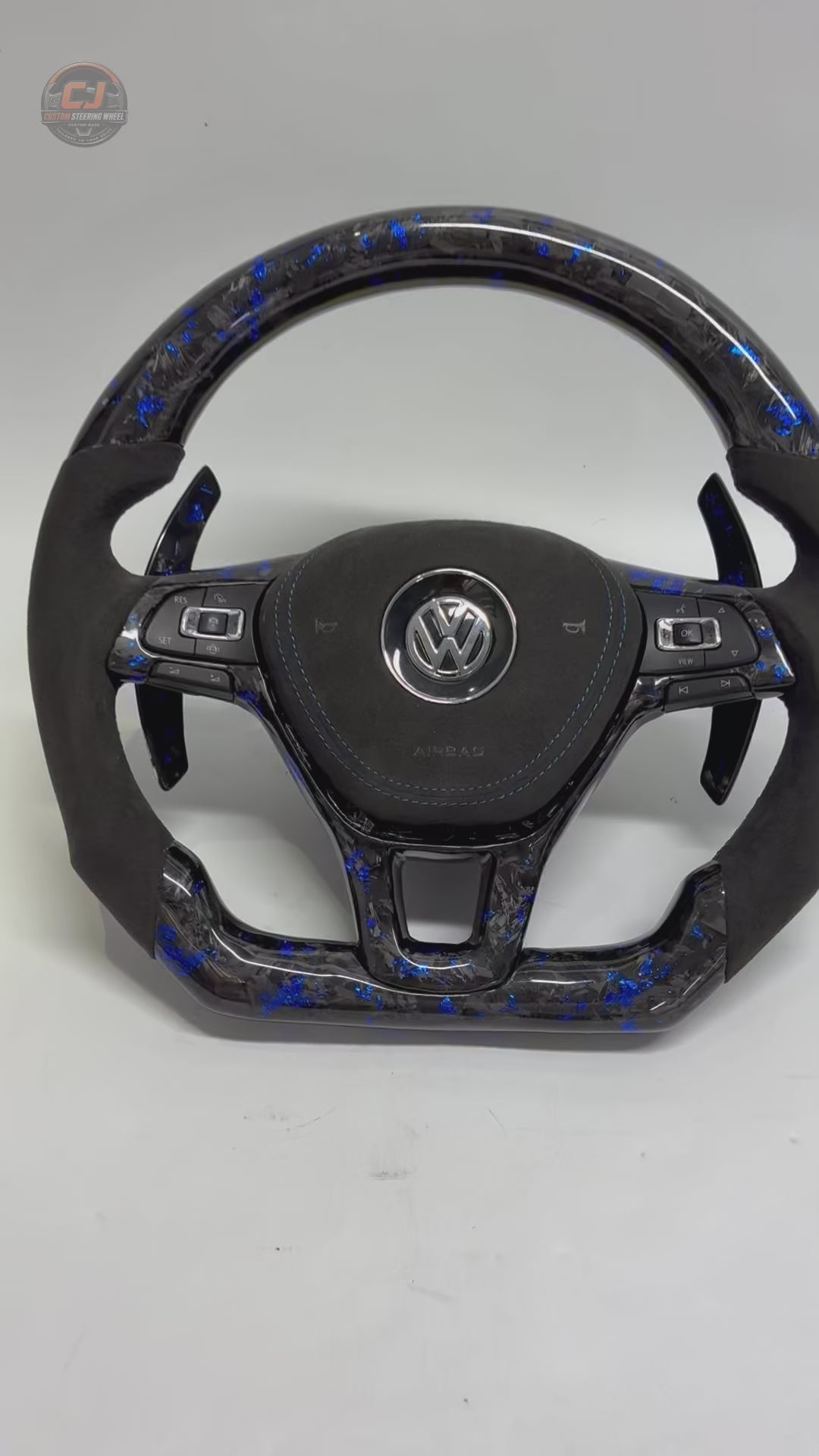 Studio showcase video displaying blue forged carbon steering wheel with Alcantara grips multifunction controls and paddle shifters for Golf 7 MK7 Passat Touareg Tiguan Polo GTD MK6 R Line CC Jetta by CJ Mod Garage