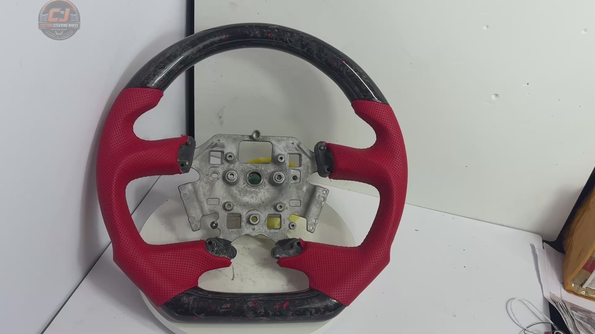 White background product video of Ford Falcon FG XR XR6 XR8 custom steering wheel in red flake forged carbon and red perforated leather by CJ Mod Garage