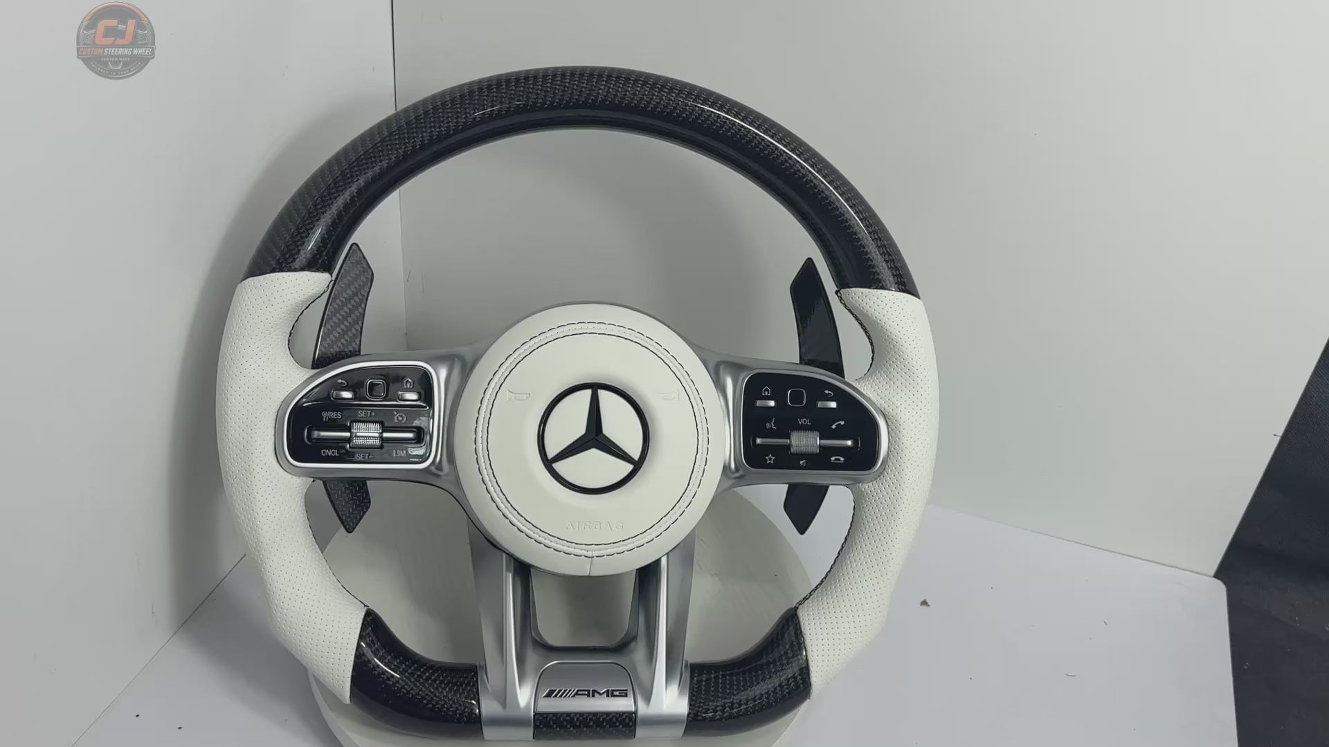 White background showcase video of Mercedes AMG custom carbon fiber steering wheel with white perforated leather grips and OEM style controls for W117 W176 W177 W203 W204 W205 W211 W212 W213 W218 C43 C63 C200 C300 by CJ Mod Garage