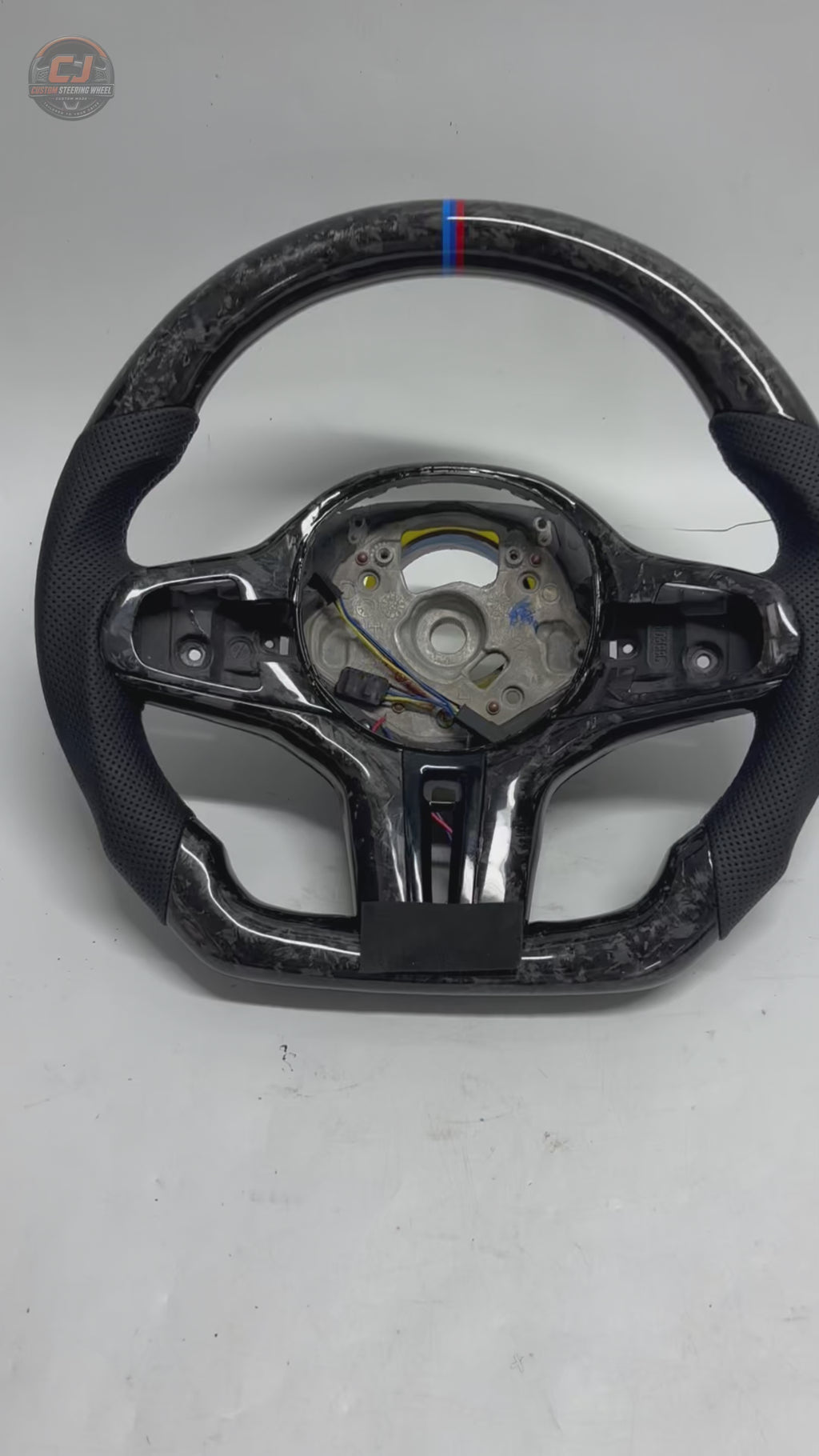 White background showcase video of CJ Mod Garage BMW forged carbon fiber steering wheel featuring premium forged carbon texture, black perforated leather grips, flat-bottom motorsport design, M tricolor 12 o’clock center stripe, OEM-style fitment and performance-inspired styling for BMW G02 G05 G06 G09 G11 G12 G15 G20 G22 G28 G29 G30 G38 G80 G82 F40 F90 models