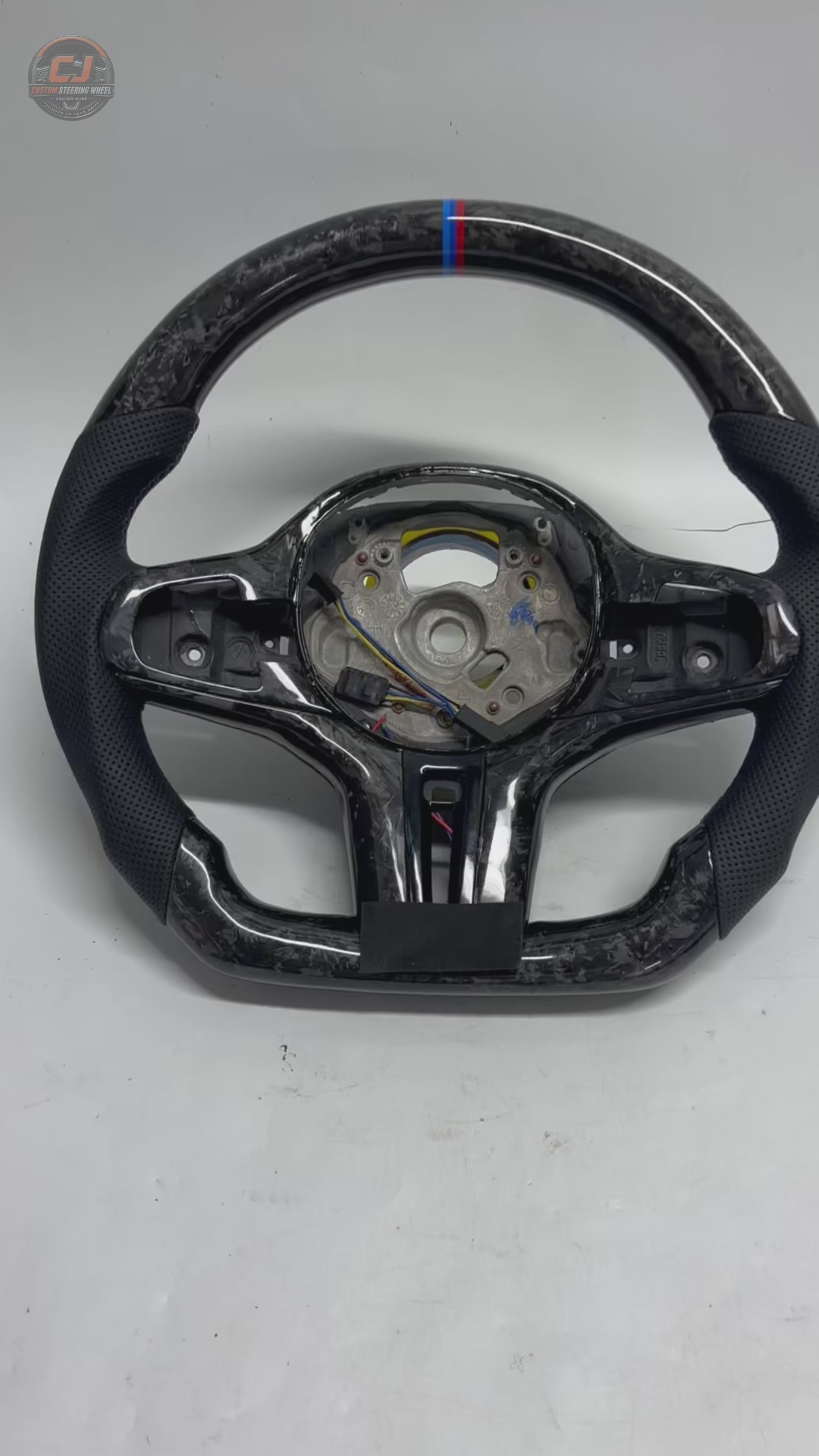 White background showcase video of CJ Mod Garage BMW forged carbon fiber steering wheel featuring premium forged carbon texture, black perforated leather grips, flat-bottom motorsport design, M tricolor 12 o’clock center stripe, OEM-style fitment and performance-inspired styling for BMW G02 G05 G06 G09 G11 G12 G15 G20 G22 G28 G29 G30 G38 G80 G82 F40 F90 models