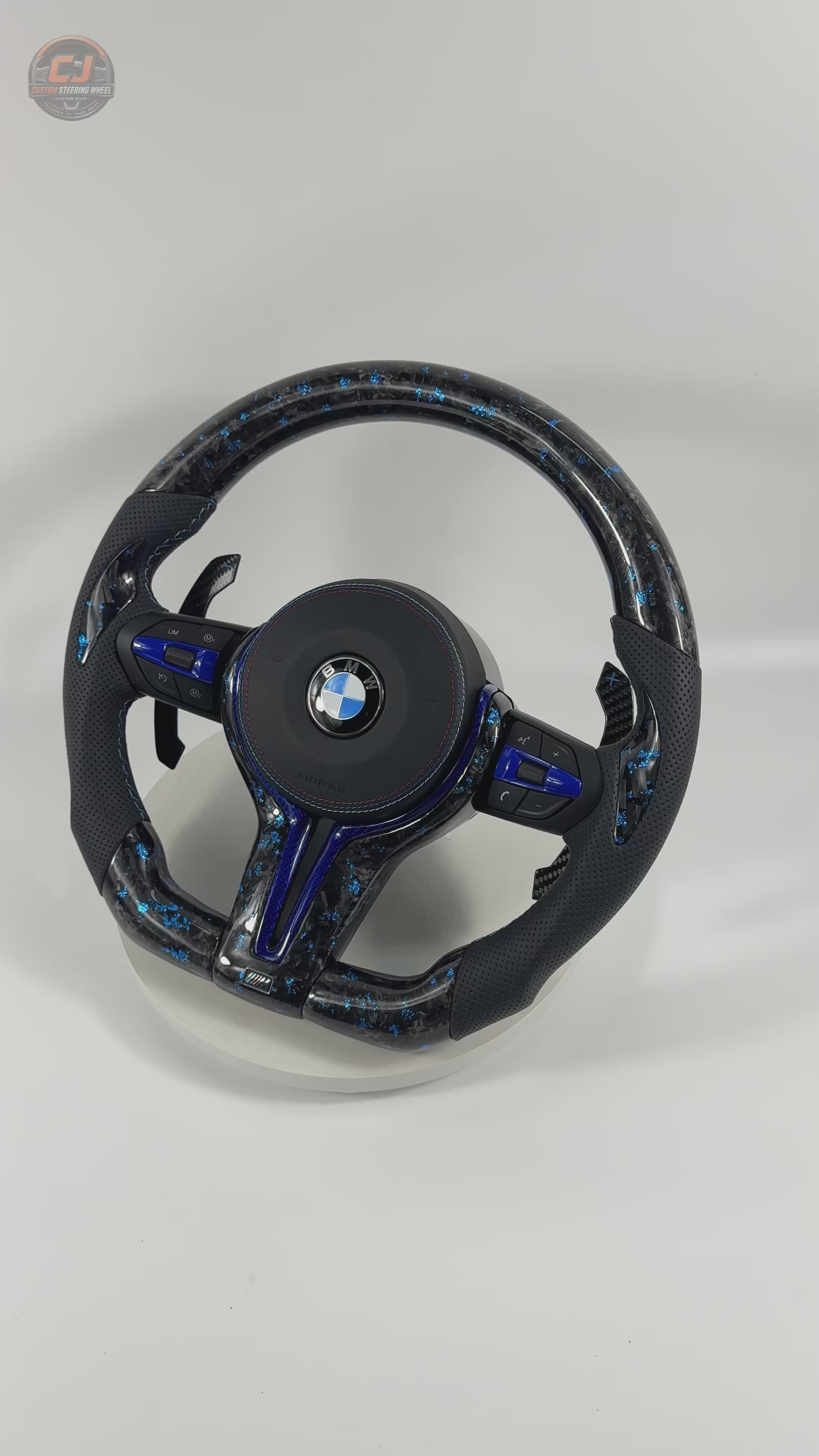 White background showcase video of BMW custom forged carbon steering wheel with blue marble flakes, blue accent trim, multifunction controls, sport grip leather, and carbon paddle shifters compatible with BMW F10 F11 F15 F18 F20 F23 F25 F30 F32 F35 F40 F80 E84 E87 E90 E92 E93