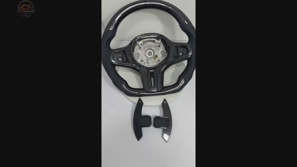 White background product showcase video of BMW G-chassis gloss carbon fiber steering wheel featuring perforated leather grips, flat-bottom OEM+ performance styling, round airbag fitment, and sport grip contour compatible with BMW G02 G05 G06 G09 G11 G12 G15 G20 G22 G28 G29 G30 G38 G80 G82 F40 F90
