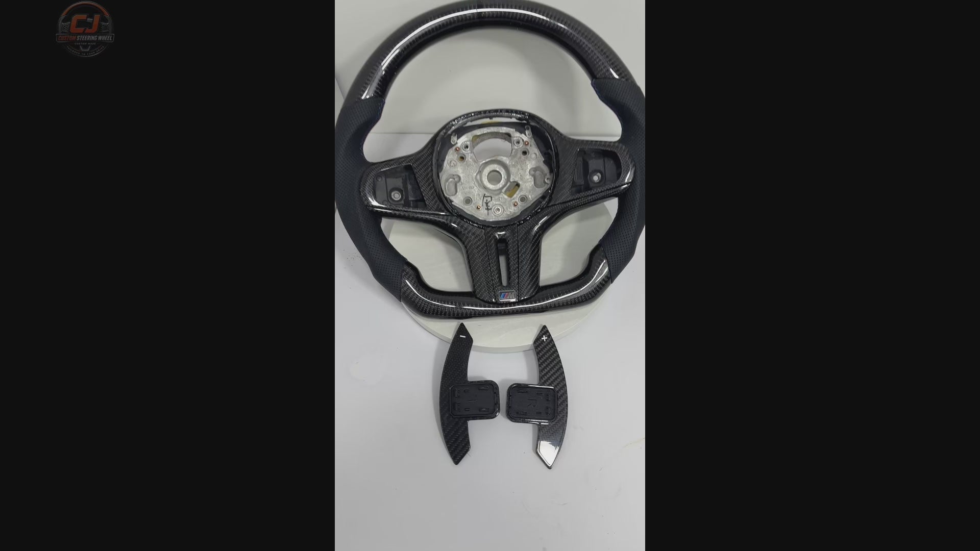 White background product showcase video of BMW G-chassis gloss carbon fiber steering wheel featuring perforated leather grips, flat-bottom OEM+ performance styling, round airbag fitment, and sport grip contour compatible with BMW G02 G05 G06 G09 G11 G12 G15 G20 G22 G28 G29 G30 G38 G80 G82 F40 F90