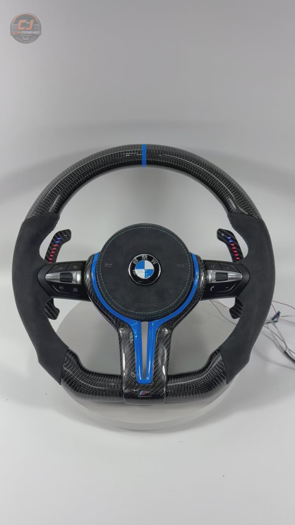 White background product showcase video of custom BMW carbon fiber steering wheel with blue trim, Alcantara leather grips, LED paddle shifters, multifunction buttons, and OEM-style fitment for BMW F10 F11 F15 F18 F20 F23 F25 F30 F32 F35 F40 F80 E84 E87 E90 E92 E93