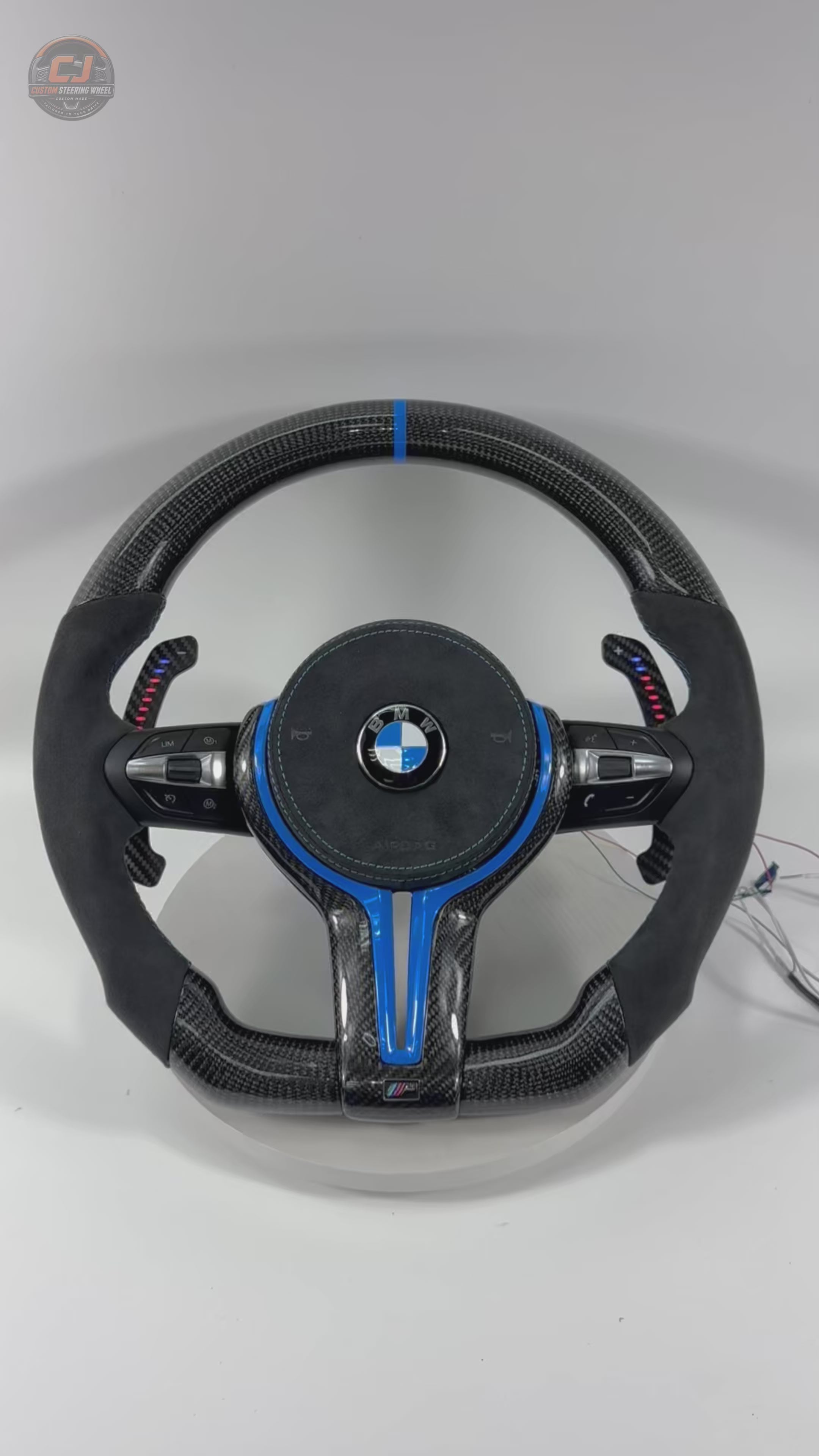White background product showcase video of custom BMW carbon fiber steering wheel with blue trim, Alcantara leather grips, LED paddle shifters, multifunction buttons, and OEM-style fitment for BMW F10 F11 F15 F18 F20 F23 F25 F30 F32 F35 F40 F80 E84 E87 E90 E92 E93