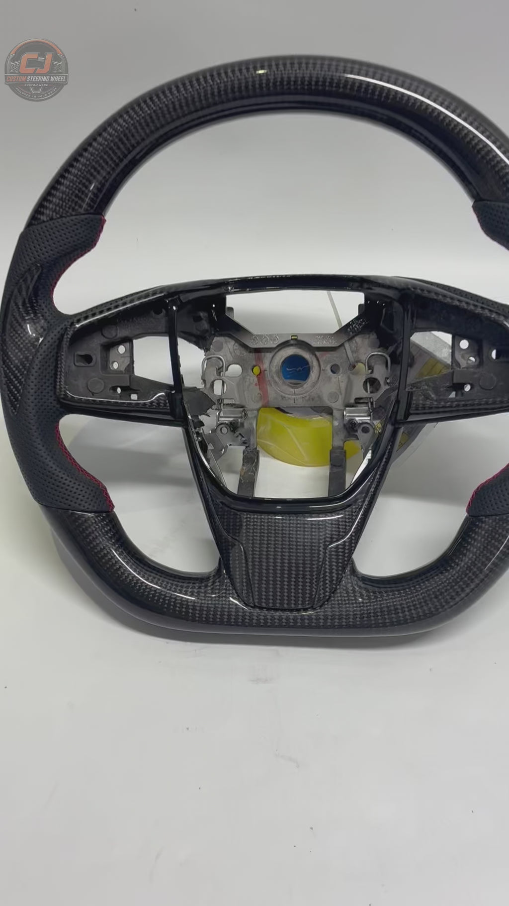 Honda Civic 10th Gen carbon fiber steering wheel rotating on white background with perforated leather grips red stitching and OEM fitment design by CJ Mod Garage