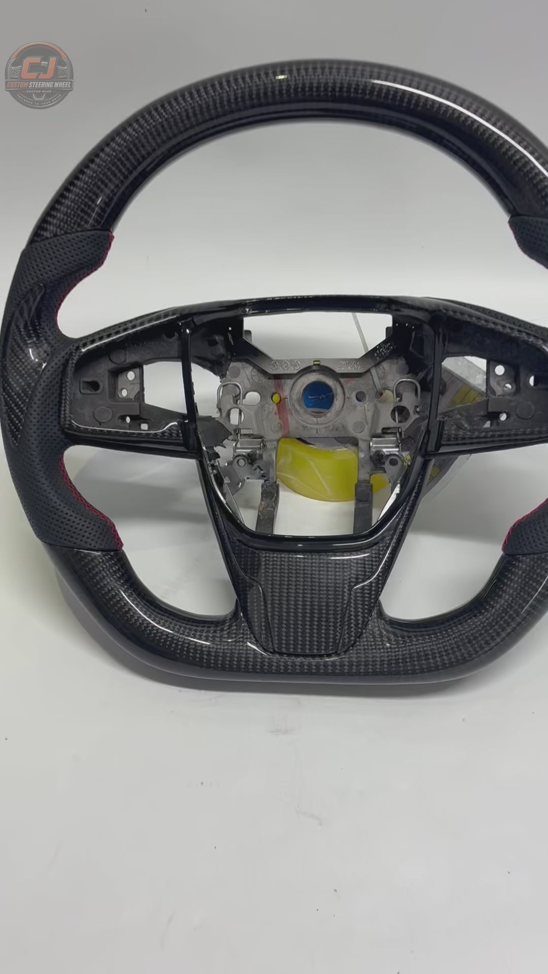 Honda Civic 10th Gen carbon fiber steering wheel rotating on white background with perforated leather grips red stitching and OEM fitment design by CJ Mod Garage